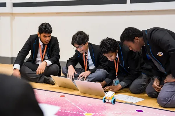 Secondary students programming SPIKE Prime robots with Python on laptops during an Advanced STEMbotics workshop