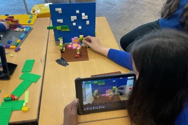 Student filming a LEGO stop-motion scene frame by frame using Stop Motion Studio on an iPad