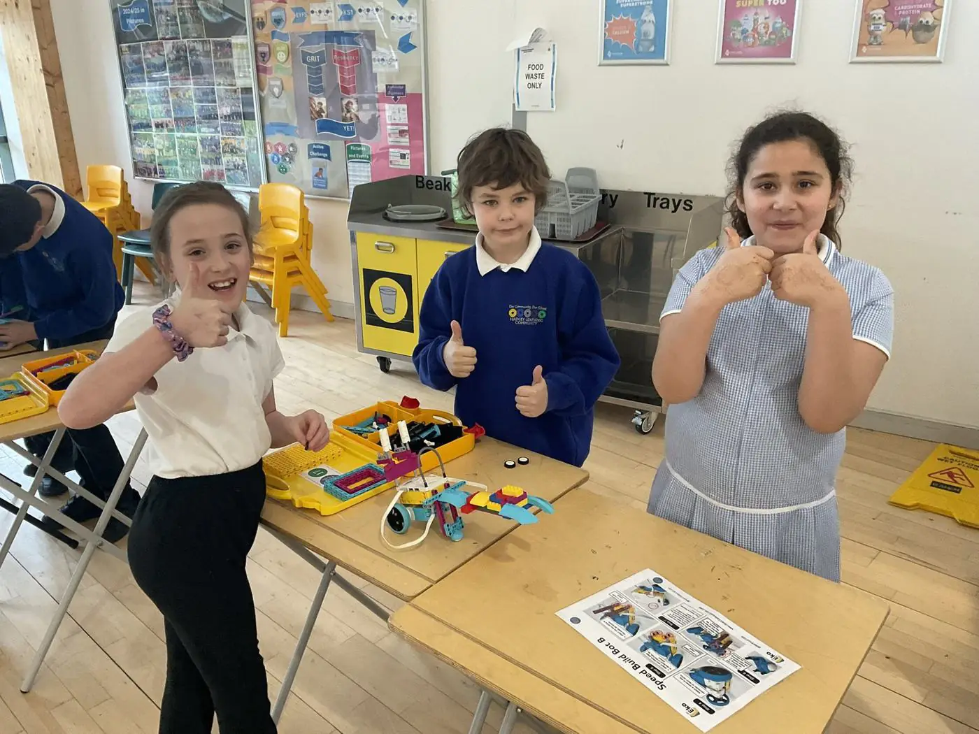 Three pupils giving thumbs up beside their completed EKO robot