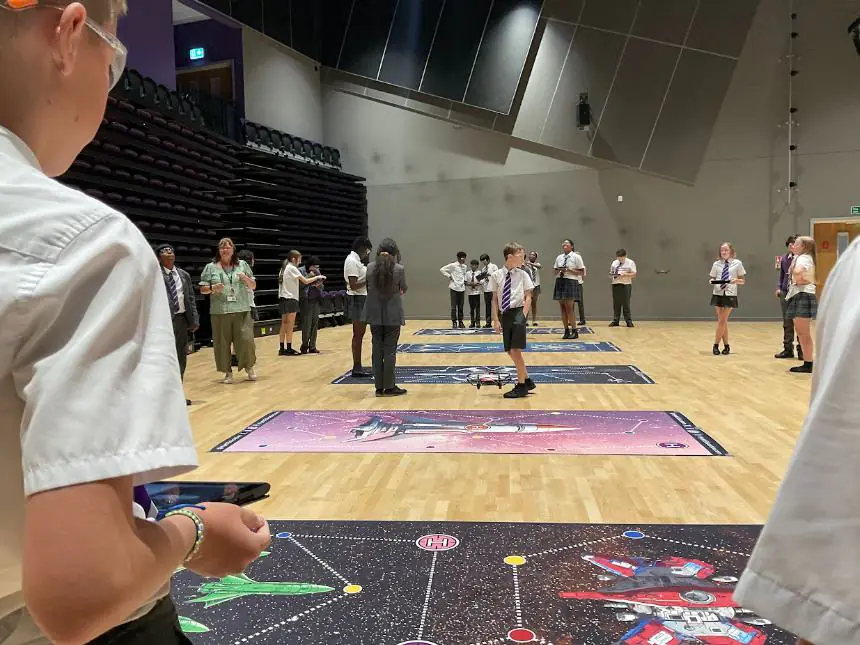 Students flying drones along flight paths on themed floor mats