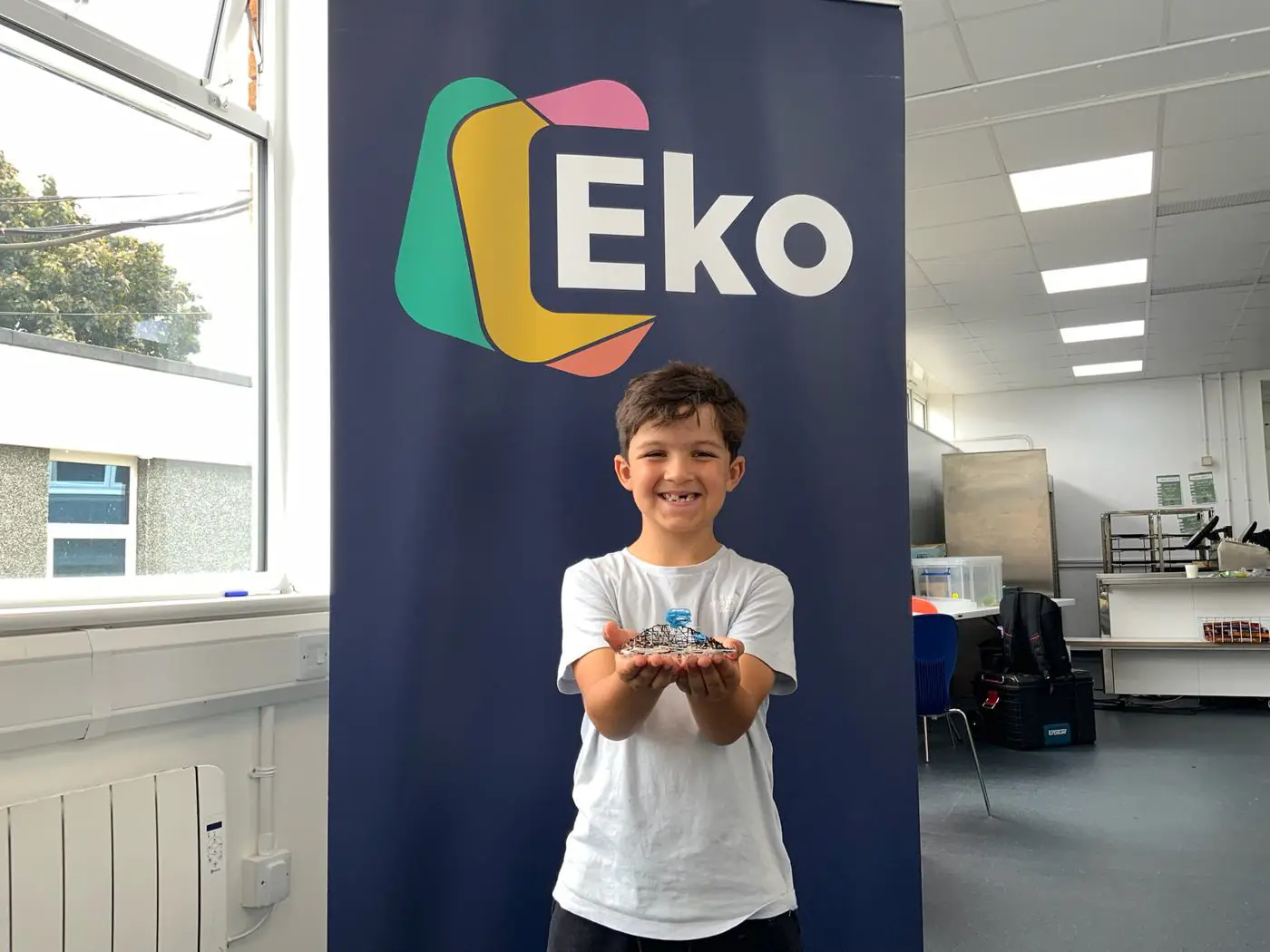 A child holding a 3D creation in front of an EKO banner