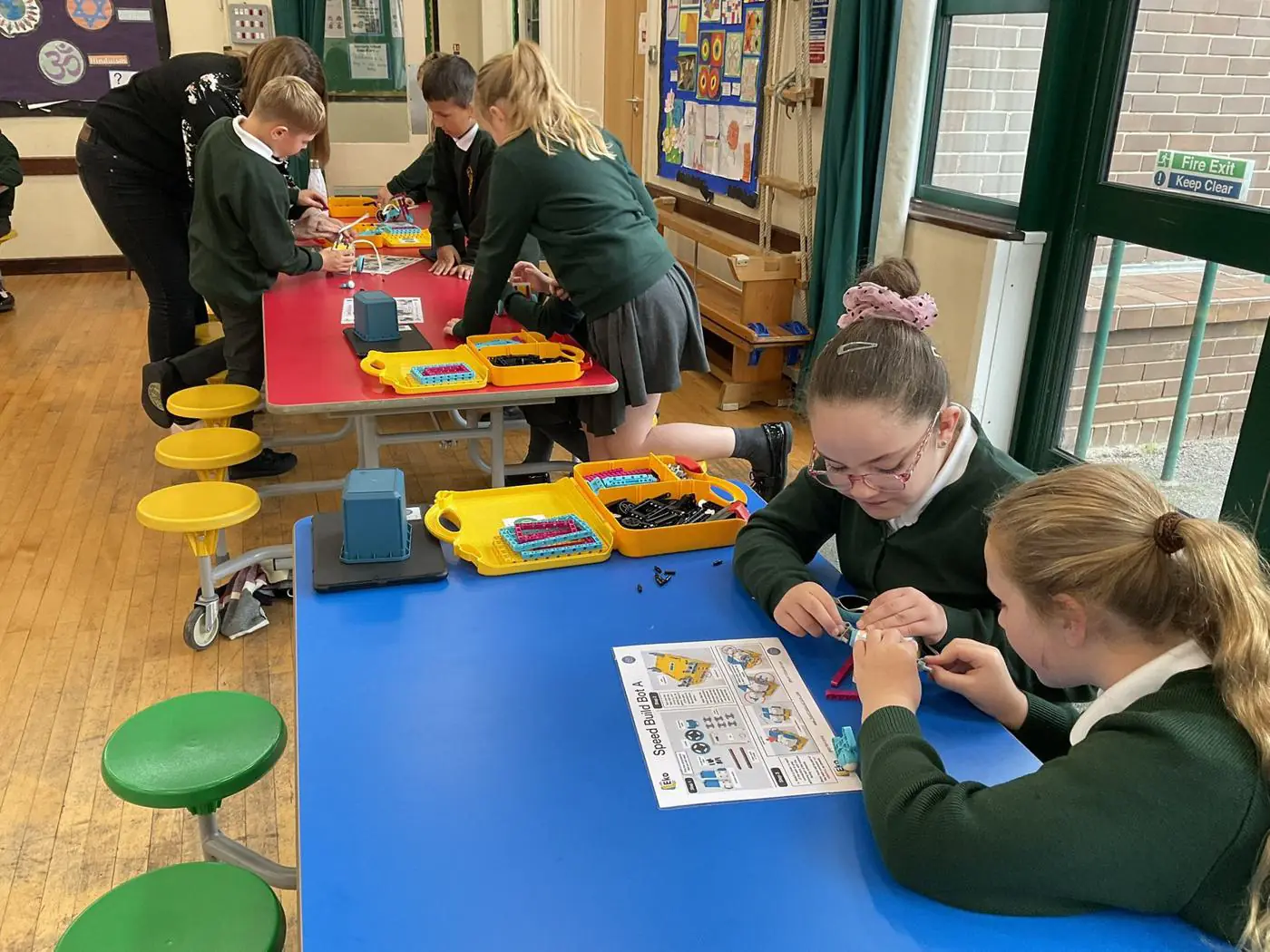 Pupils building a robot at a table with kit trays
