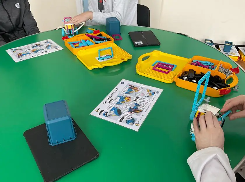 Students at a table building robots from kit trays