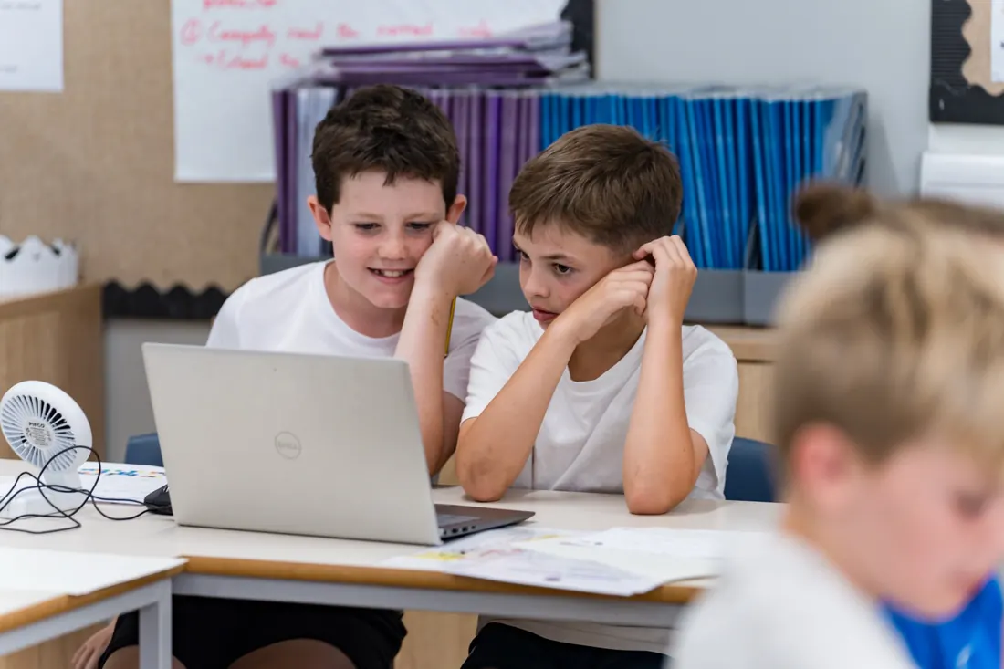Two pupils working through a cyber security challenge on a laptop