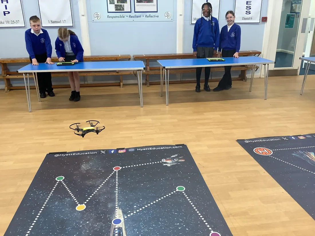 A coded drone flying over a challenge mat as pupils watch