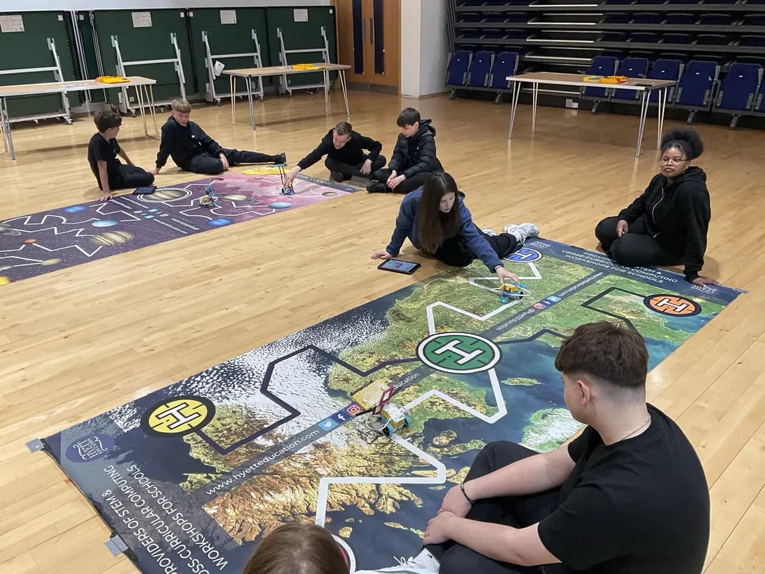 Secondary students coding robots on a map challenge mat