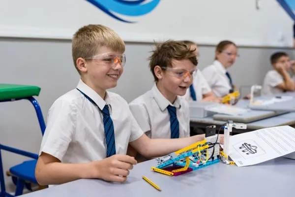 Two boys wearing safety goggles with their completed AI-powered flight response catapult during an AI workshop