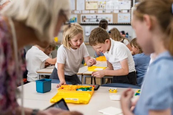 Children building with LEGO SPIKE Essential kits at classroom tables during a Beginner STEMbotics robotics workshop