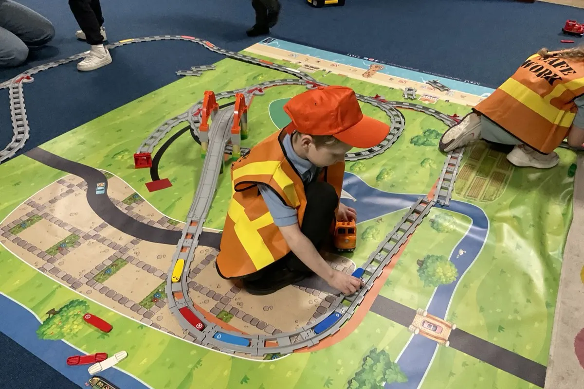 Two young girls giving thumbs up with their completed LEGO coding project