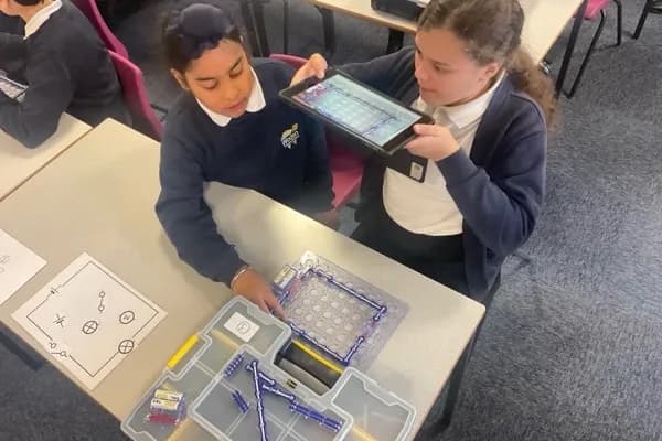 Two girls building a Snap Circuits project together, connecting electronic components on a circuit board