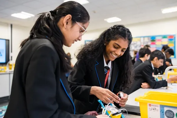 Year 7 students in school blazers working in pairs on a SPIKE Prime robot during an Intermediate STEMbotics workshop