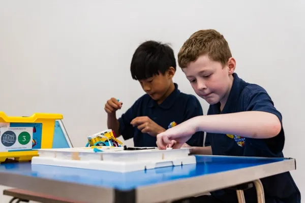 Two children focused on building LEGO SPIKE Prime robots at a table during a funded robotics workshop