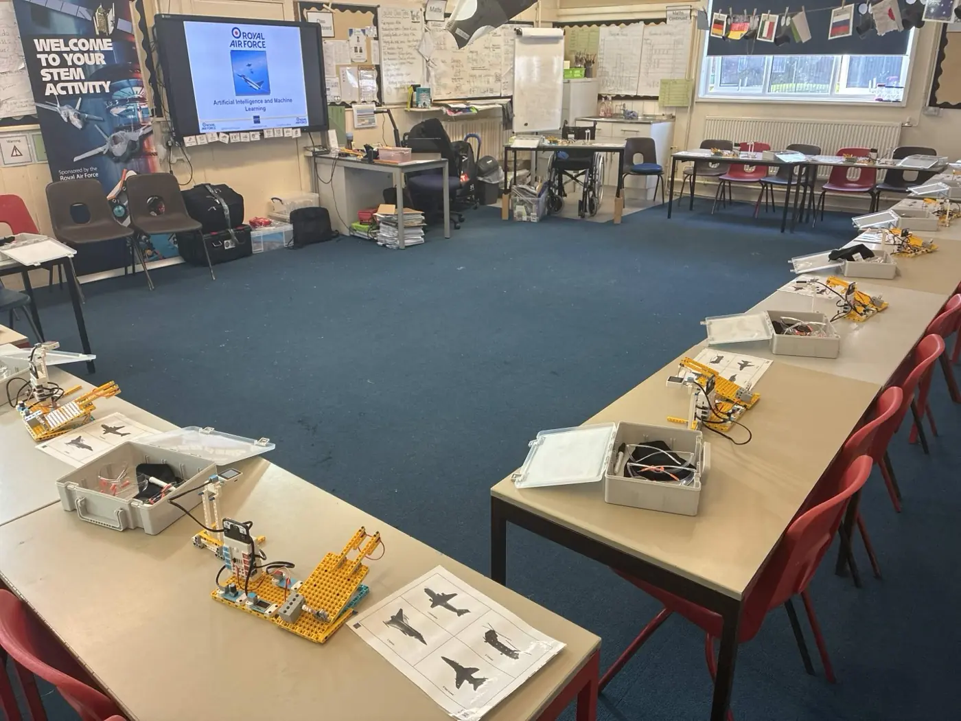 A classroom set up for AI and Machine Learning, with desks in groups and AI workshop kit on every station, and a screen showing the workshop at the front