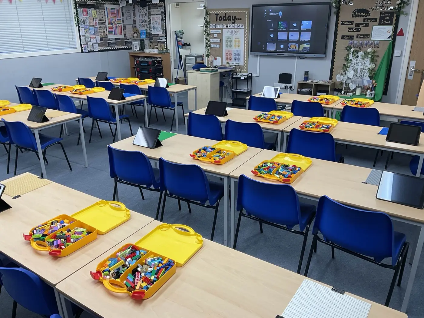 A primary classroom set up for stop-motion animation, with desks in pairs and tablets, animation kits and Lego trays at each station