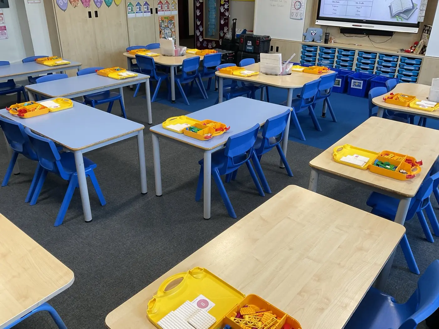 A primary classroom set up for Beginner STEMbotics, with desks in pairs and Lego-style robotics kits on each desk