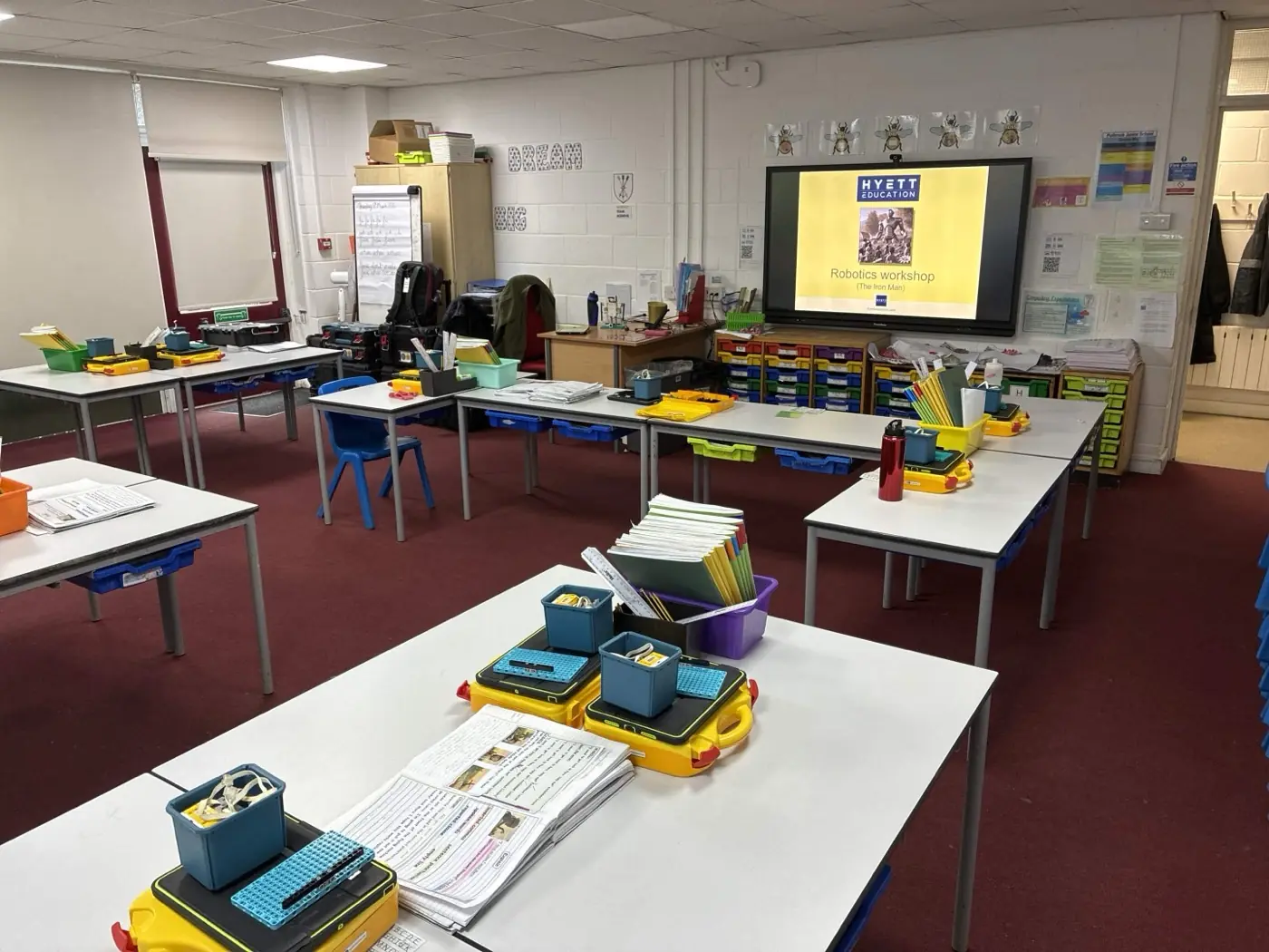 A classroom set up for Intermediate STEMbotics, with desks in groups and laptops paired with robotics kits at each station