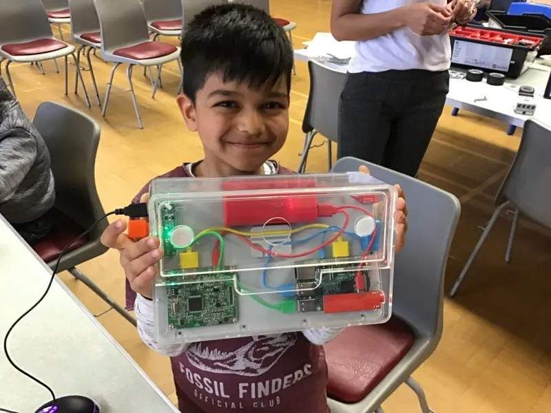 Boy proudly showing his completed robotics project